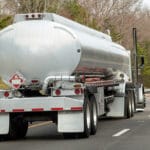 rear view of fuel truck on highway with trees in background.