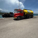 red truk with yellow water body alogn water front